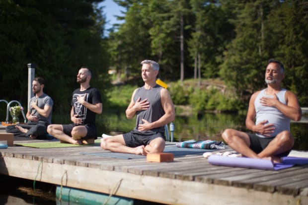 Gay yoga practitioners meditating with Men's Retreats.