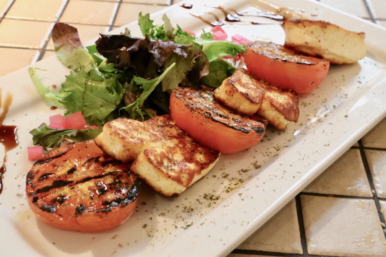 Grilled saganaki cheese is served with tomatoes and balsamic.