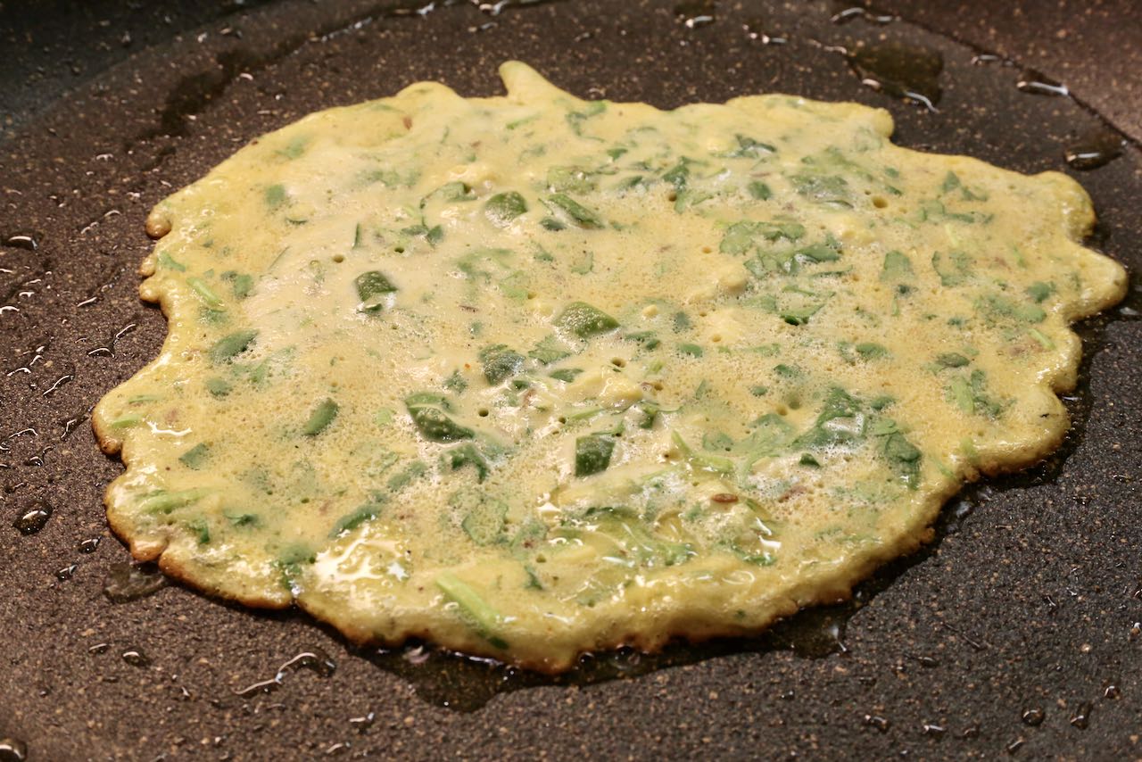 Watch the edges of the Indian crepes get crispy. Flip once the interior of the Pudla has dried.
