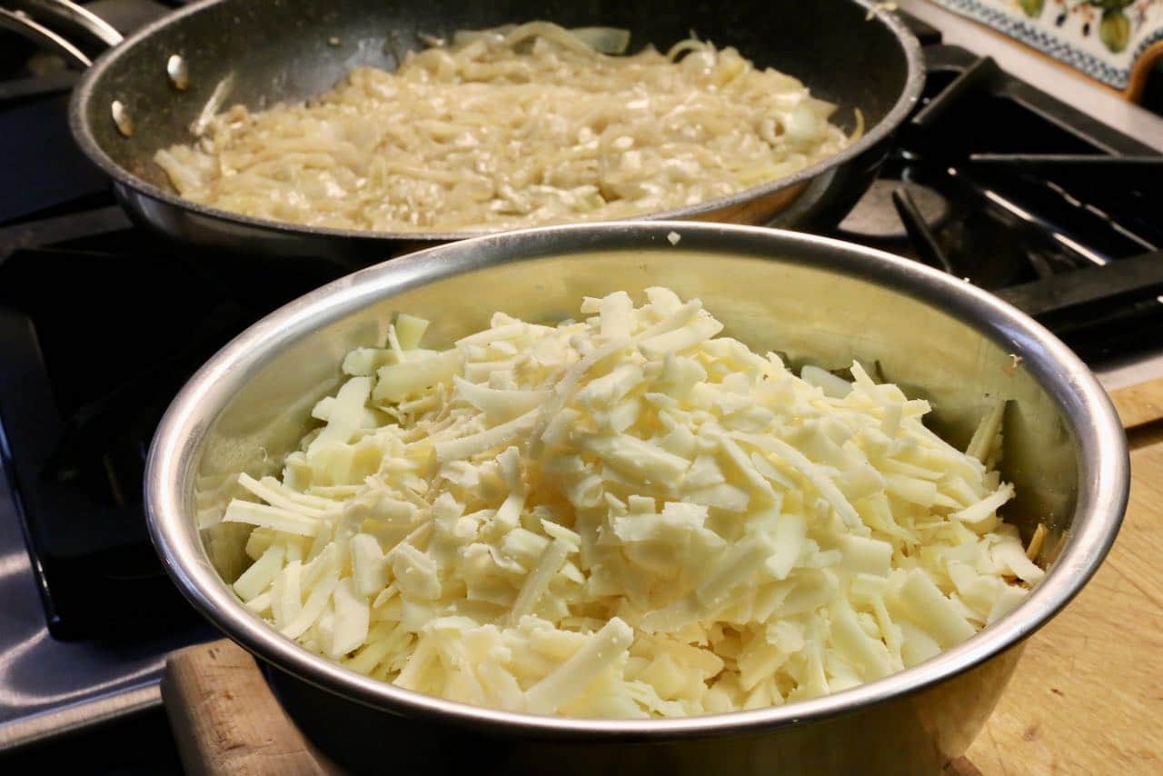 Add shredded Swiss and cheddar cheese to sautéed onions.