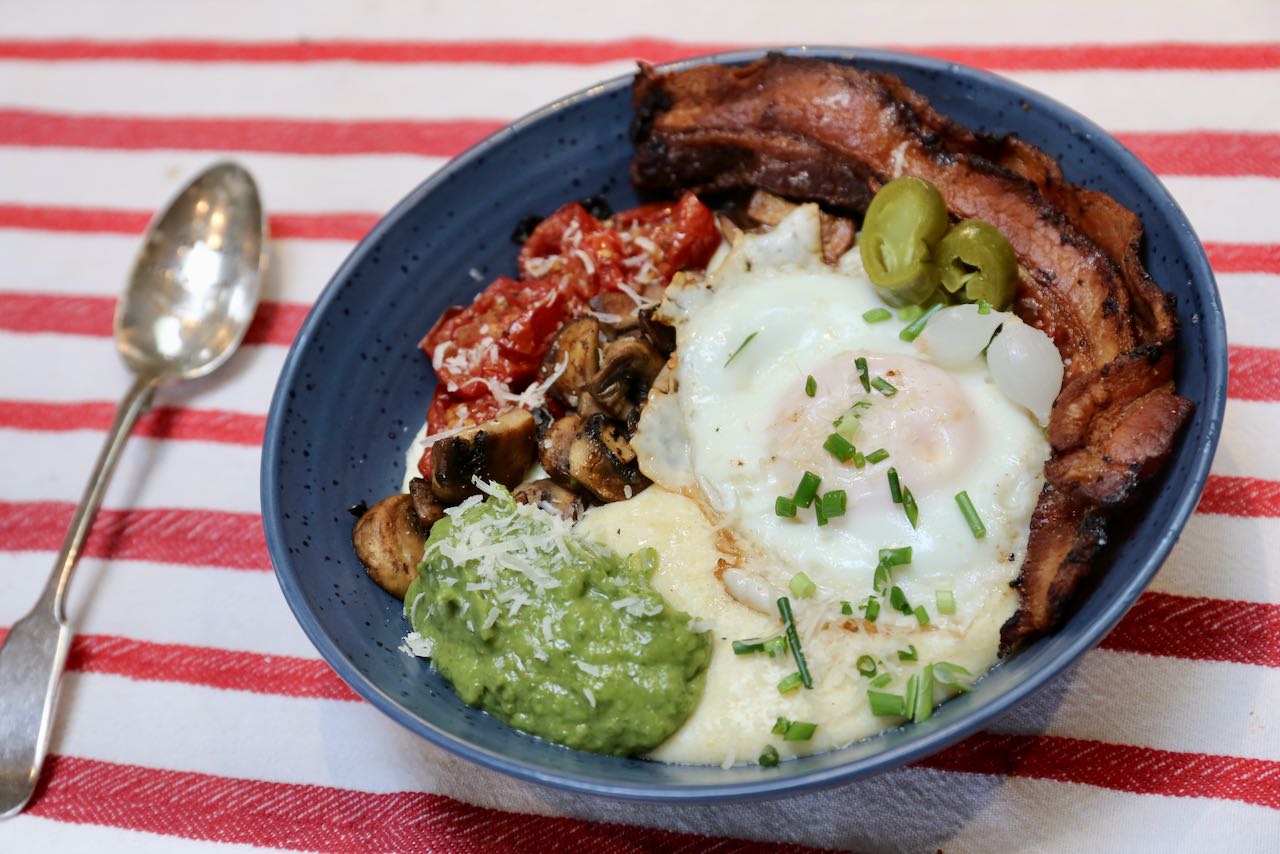 The best breakfast polenta is topped with eggs, bacon, tomatoes, mushrooms and guacamole.