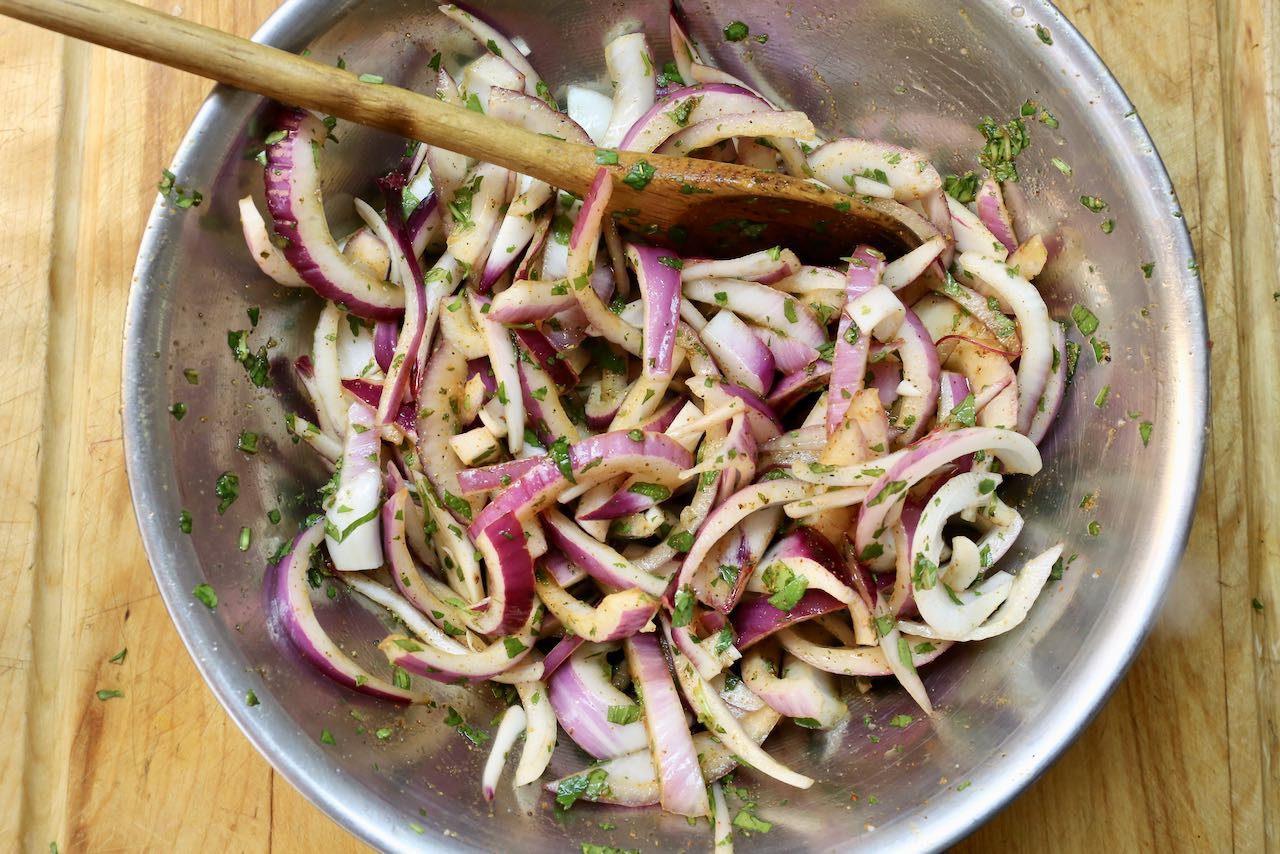 Stir herbs and spices with sliced red onions. 