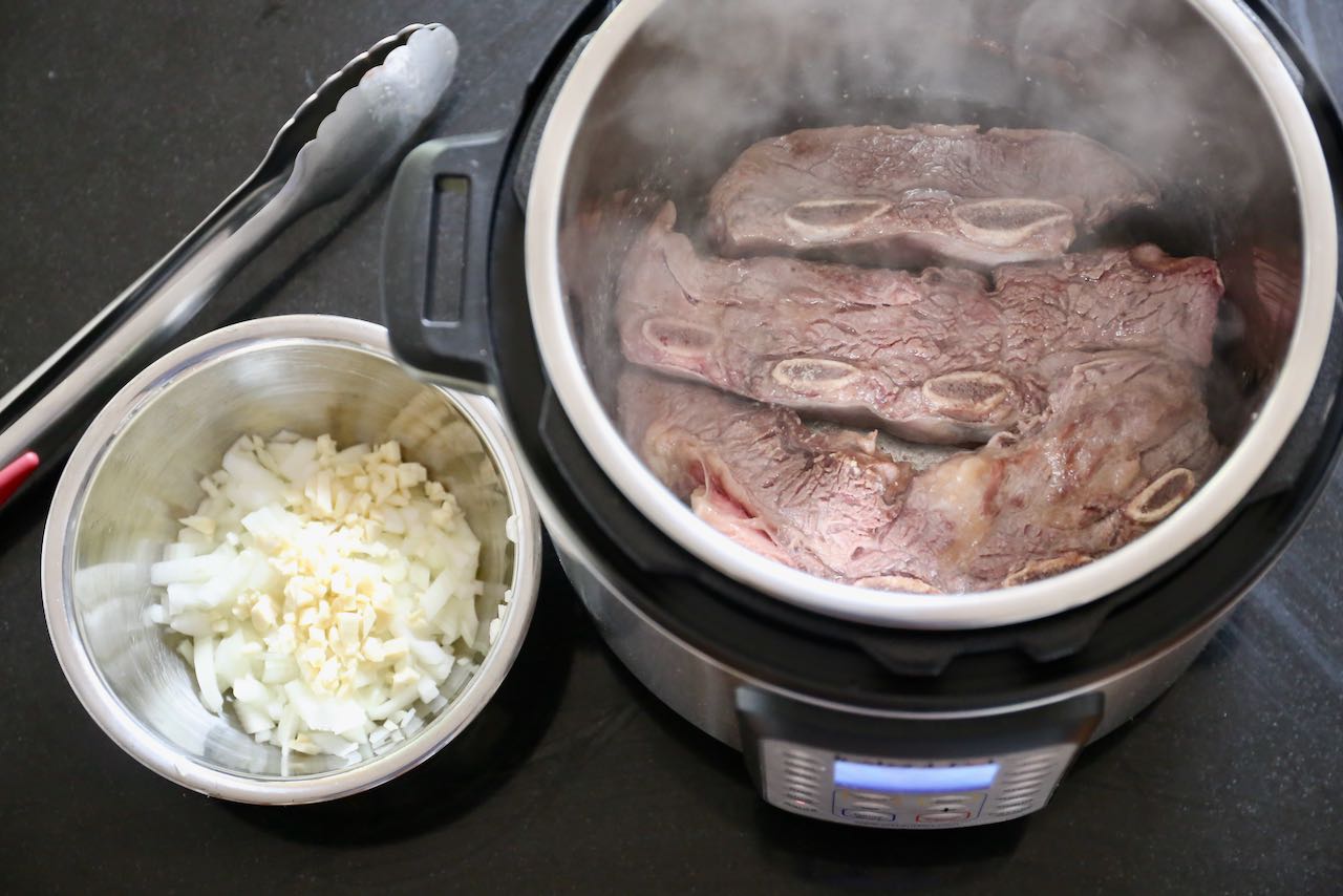 Sear seasoned short rib in your Instant Pot then sauté with minced garlic and onion.