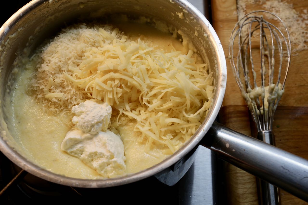 Once smooth, combine cheeses into polenta before scooping into bowls.