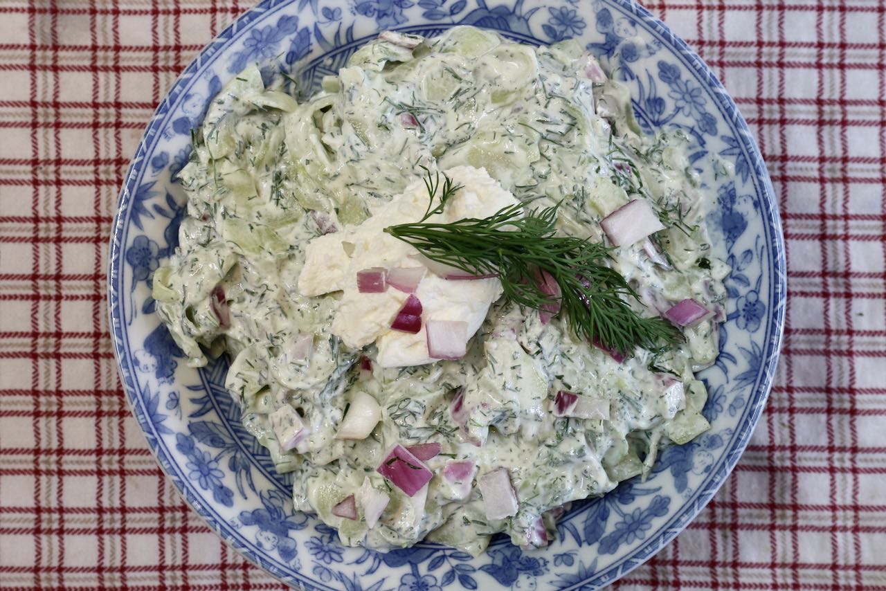 Serve Creamy Polish Cucumber Salad with sour cream, sprig of dill and red onions. 