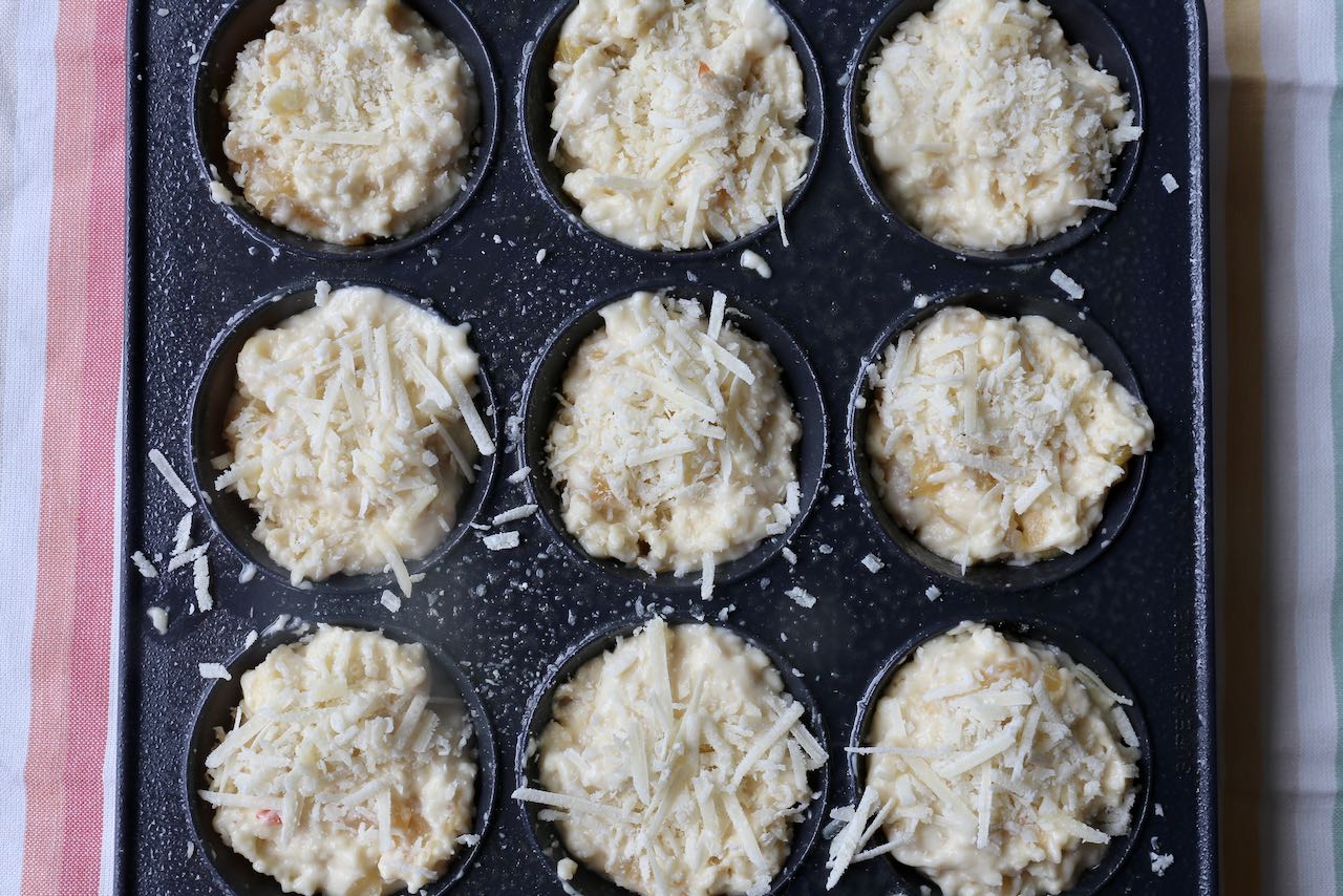 Sprinkle shredded parmesan on top of Cheese and Onion Muffins before baking in the oven.