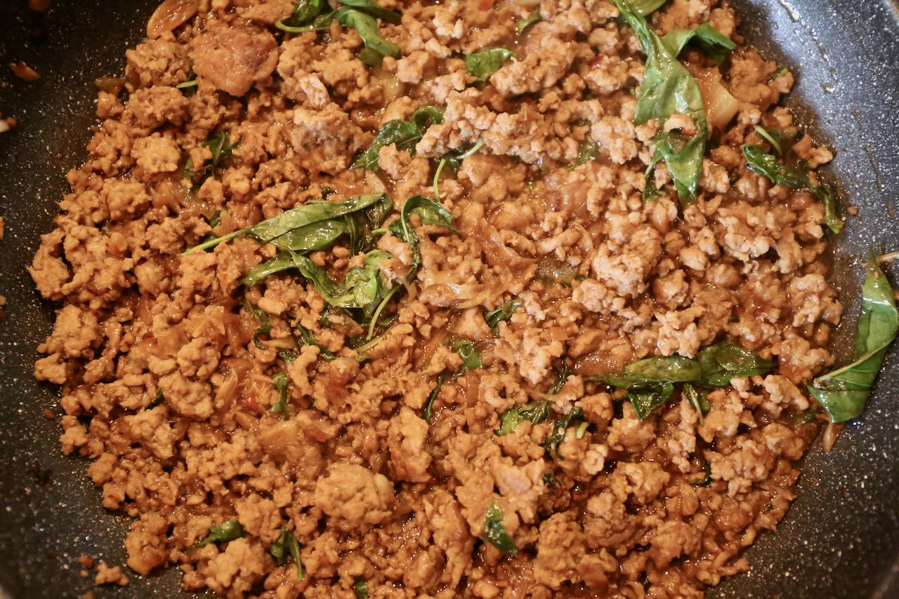 Pad Kra Pao is finished cooking once the basil has wilted in the skillet.