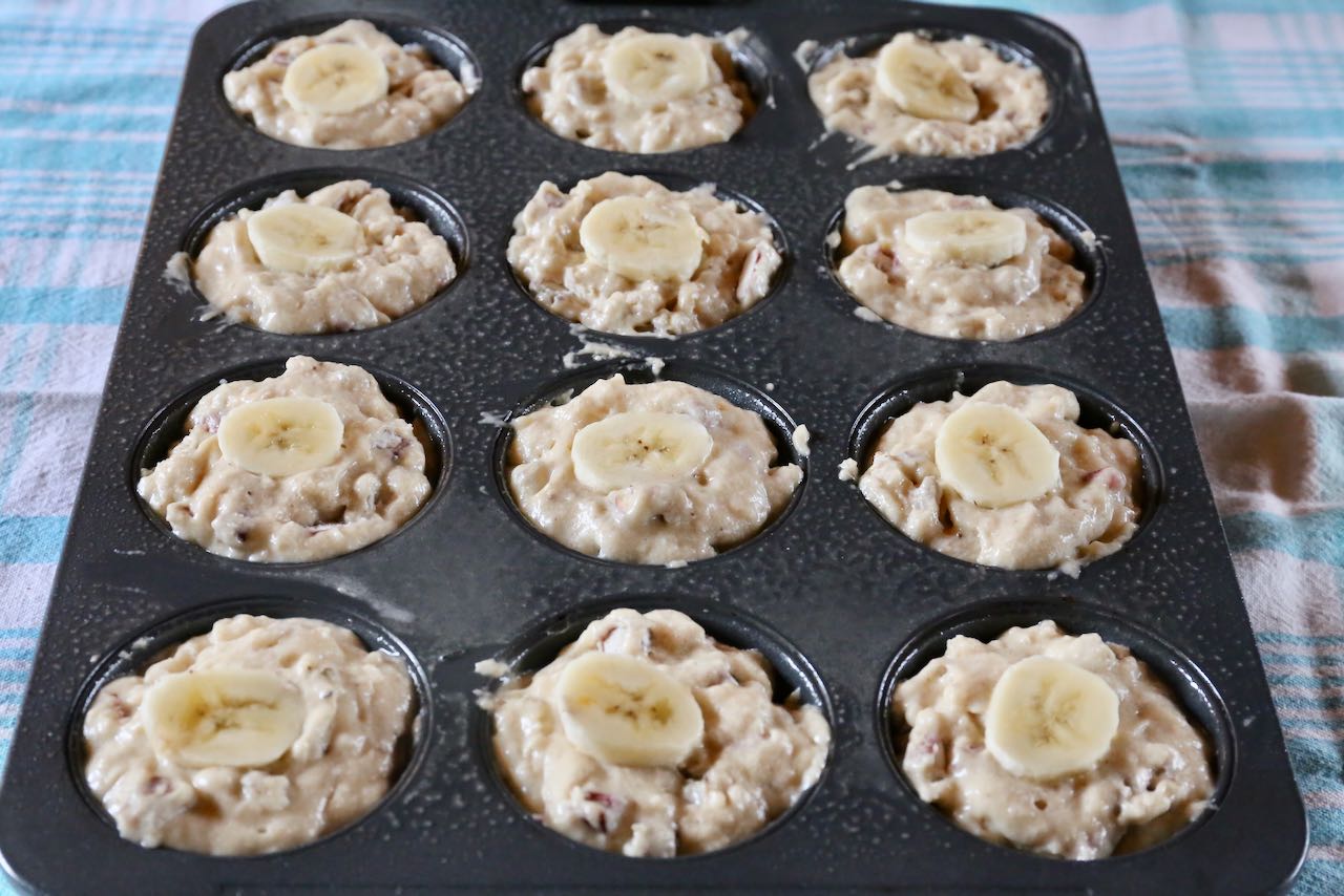 Scoop Banana Rhubarb Muffin batter into greased muffin tins and top with slice of banana.
