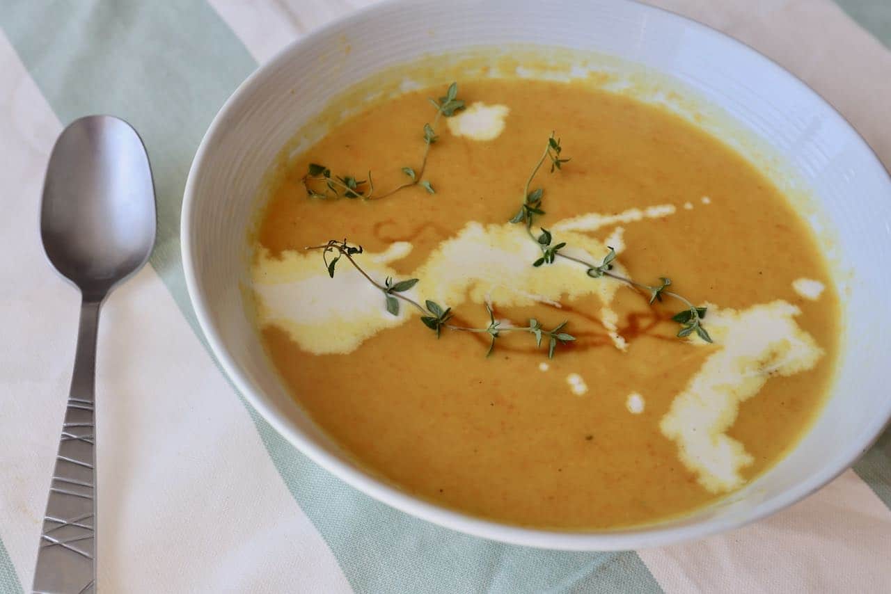 Carrot and Leek Soup is topped with cream and fresh thyme.