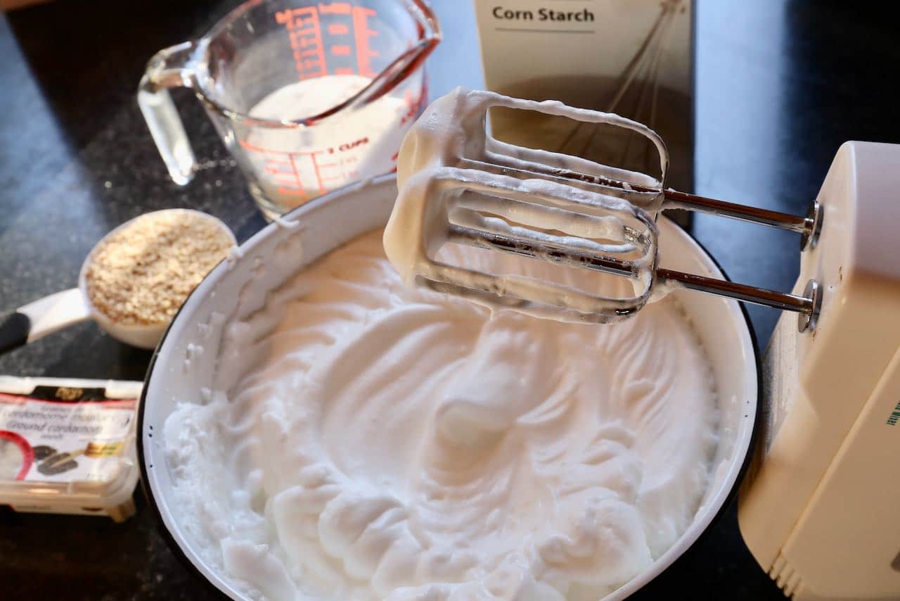 Begin making Jordgubbstårta by using egg beaters to whip meringue.