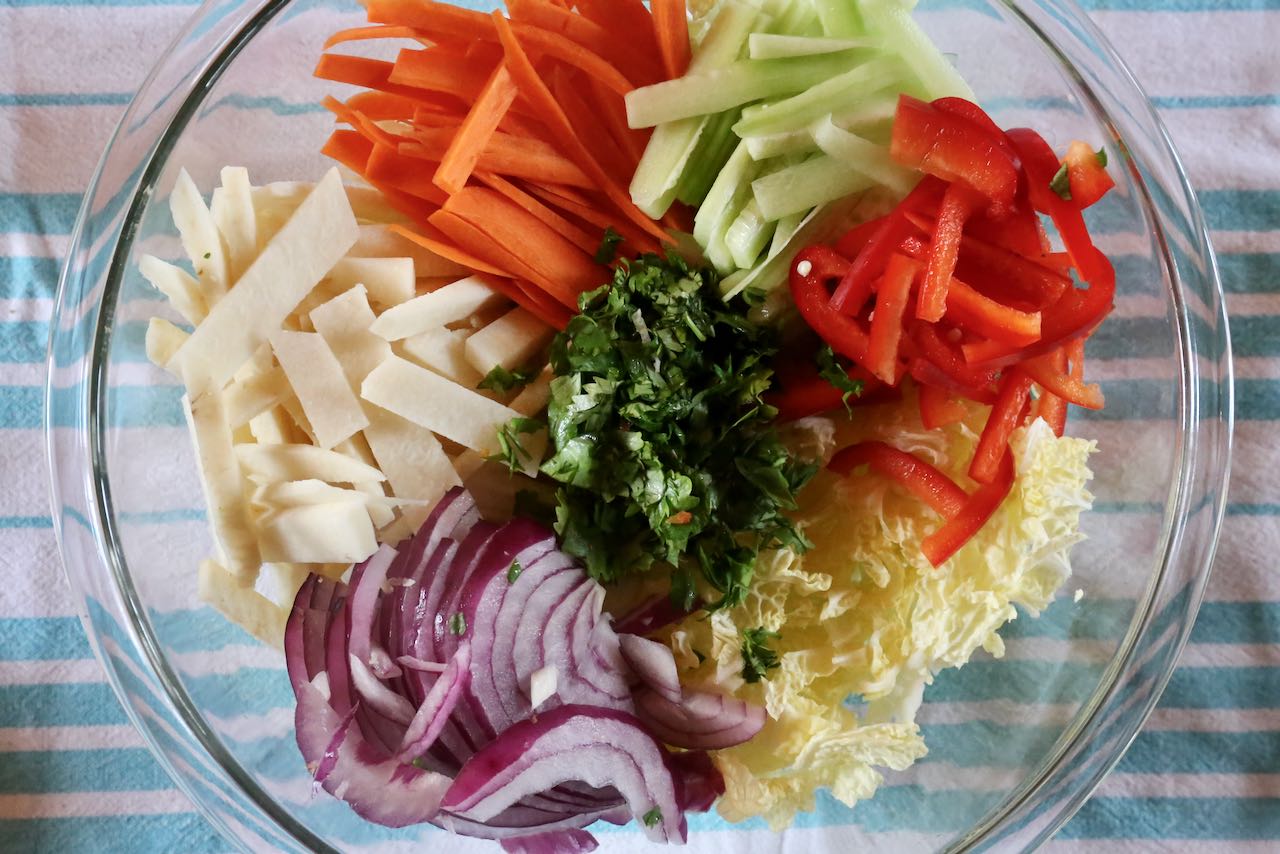 Singapore Salad  features jicama, red onion, cabbage, peppers, cucumber, carrot and cilantro.