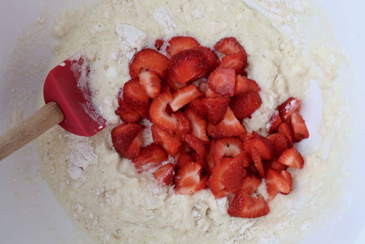 Gently combine sliced strawberries into muffin batter before scooping into greased tins.