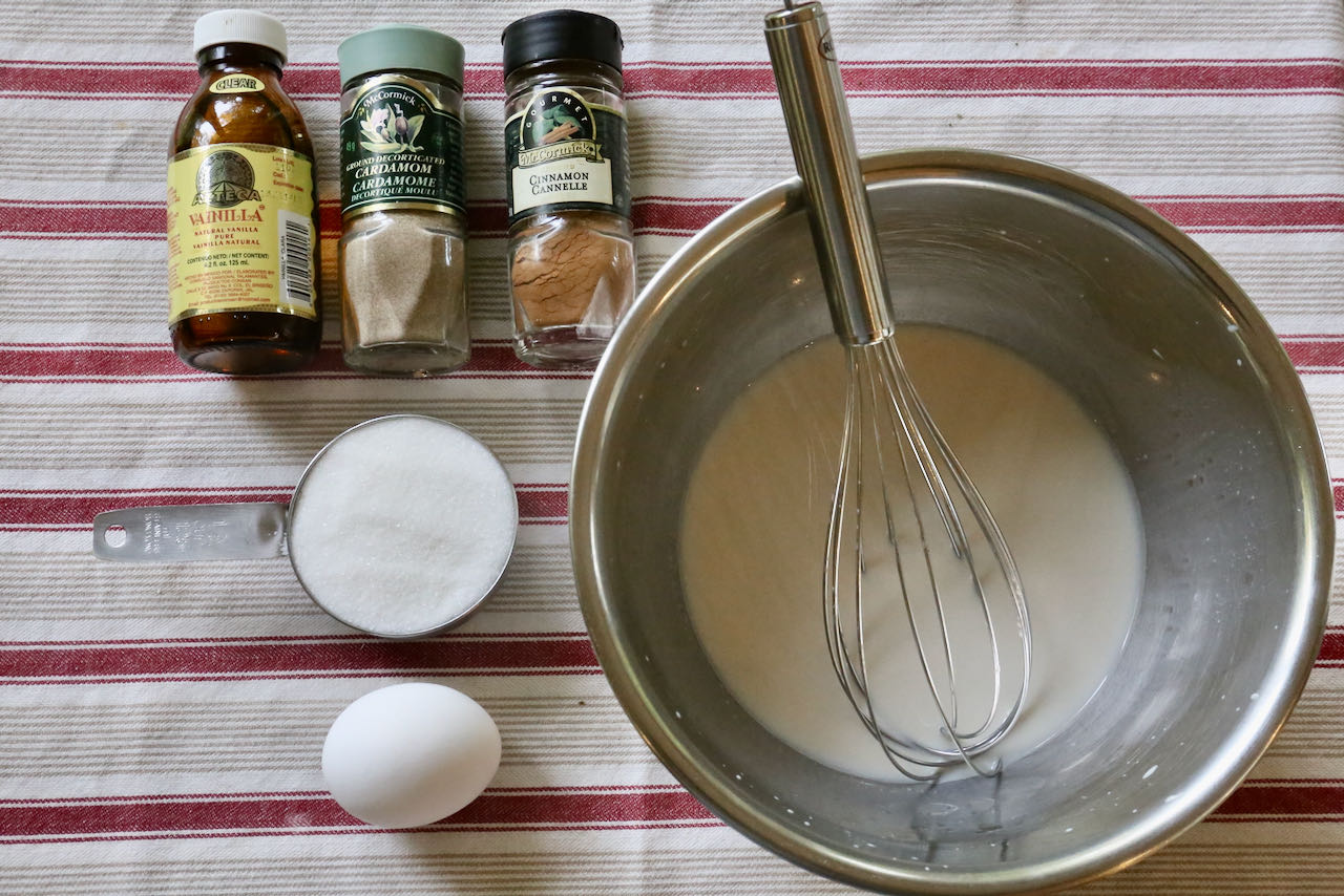 Start preparing traditional Kardemummabullar by whisking together milk, eggs, sugar spices and vanilla.