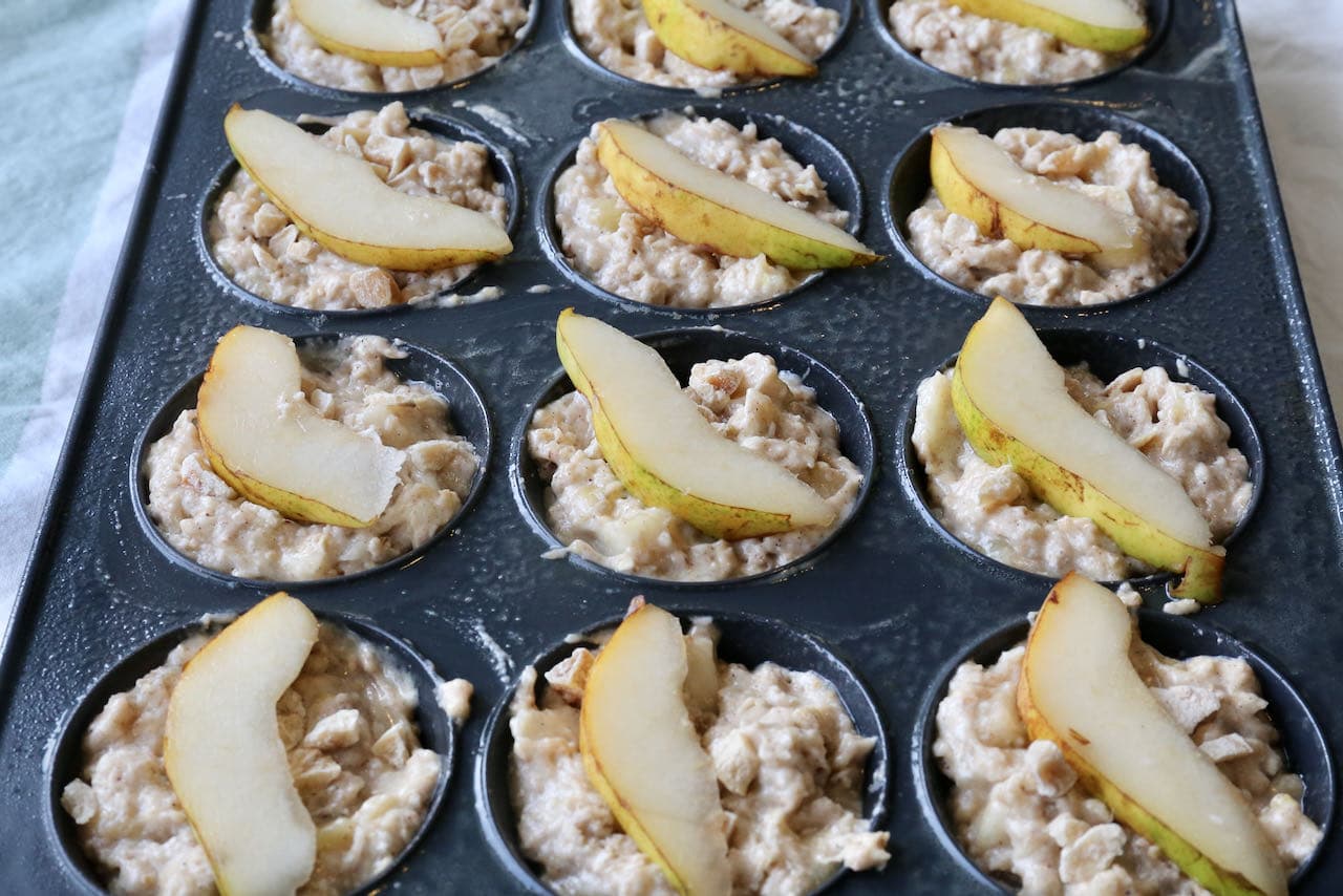 Fill each greased muffin cup 3/4 full with batter and top with crystalized ginger and thinly sliced pear.