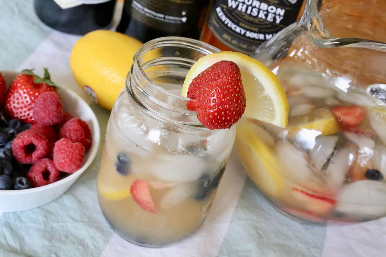 Garnish your Summer Whiskey Cocktail with fresh strawberries and lemon slice.