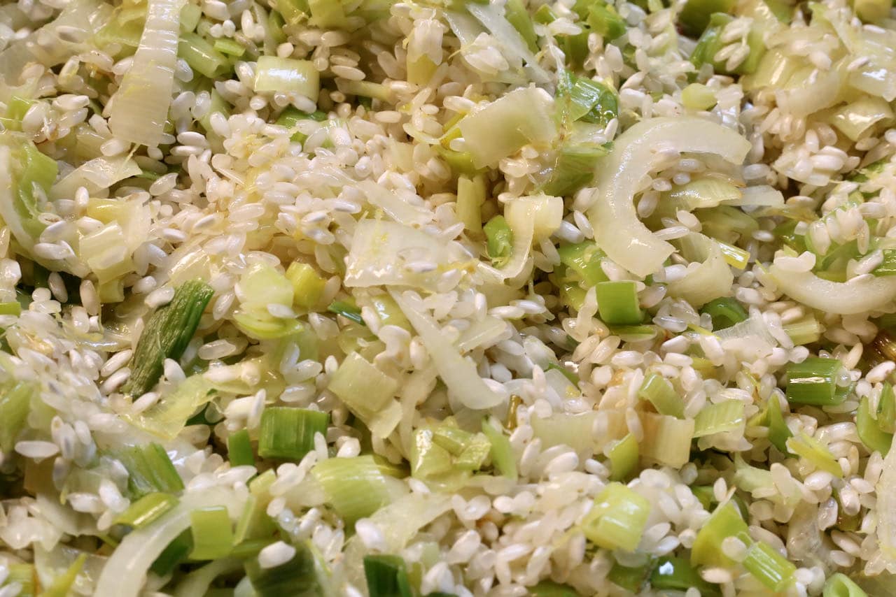 Saute butter, olive oil, sliced leeks and arborio rice before slowly adding chicken broth.