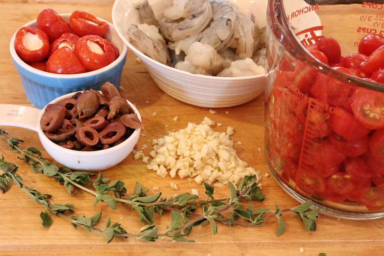 Homemade Garides Saganaki features sliced olives, minced garlic, cherry tomatoes and fresh shrimp. 