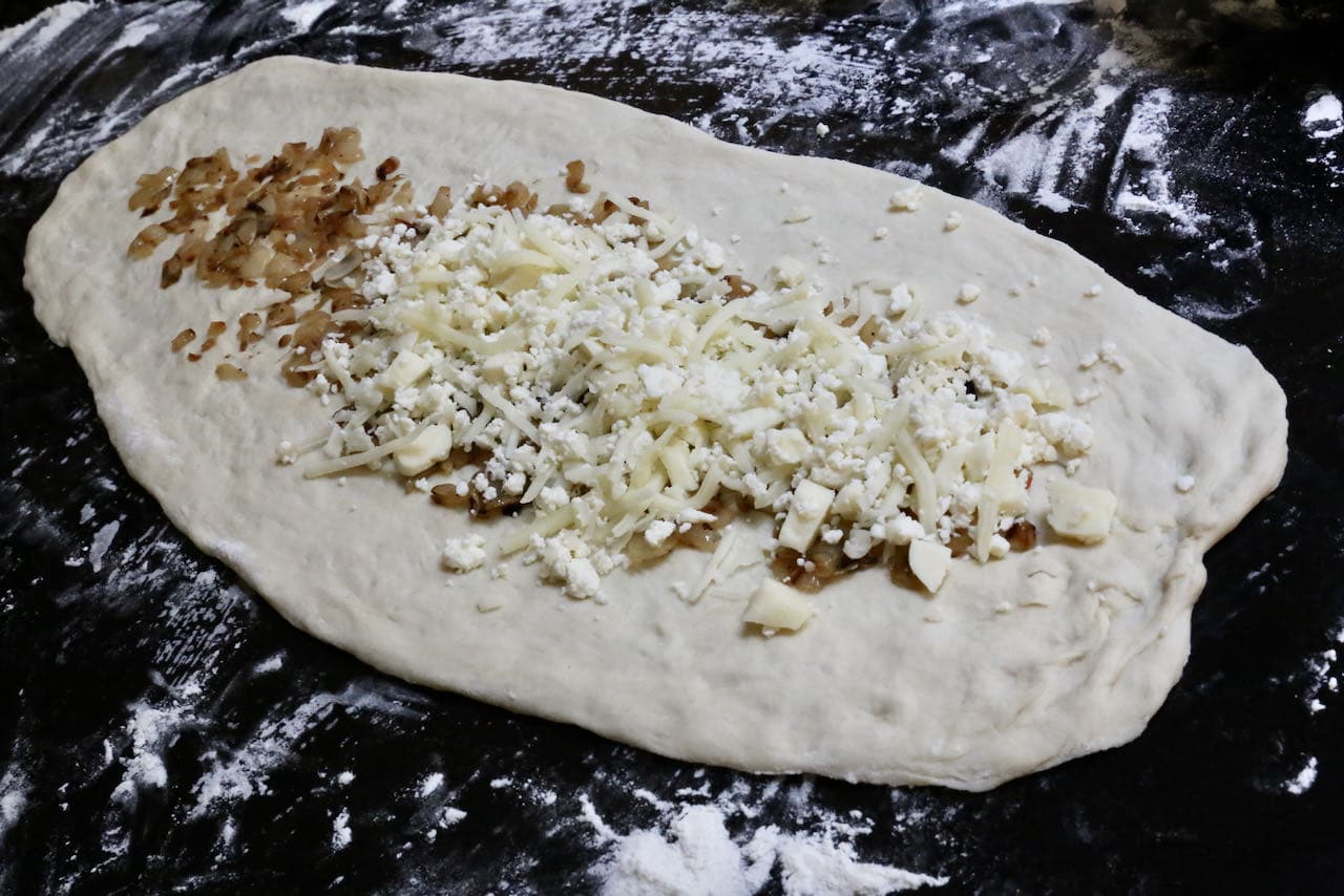 Fill Peynirli Pide dough with fried onions, shredded cheese and crumbled feta. 