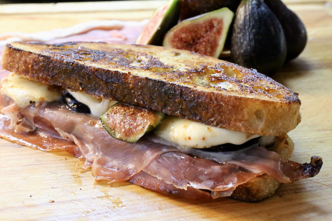 Slice each Prosciutto Grilled Cheese in half with a serrated bread knife and place on a plate.