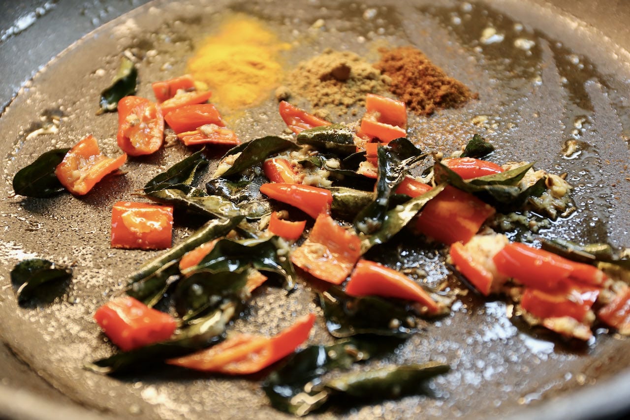 Masala Poppadom: Begin preparing Papad Ki Subji by frying red chili, curry leaf and spices in a skillet.