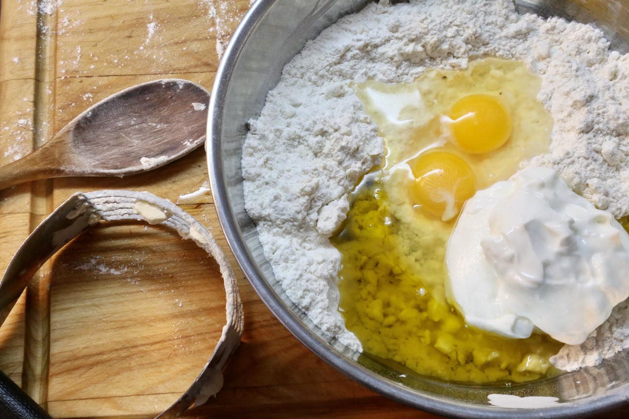 Pogaca Recipe Dough: Mix together flour, salt, baking powder, cold butter, eggs, olive oil and greek yogurt.