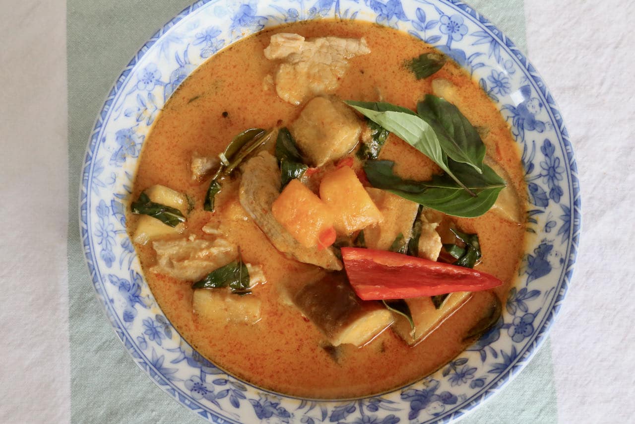 Garnish Pork Thai Curry with sliced chillies and fresh basil leaves. 