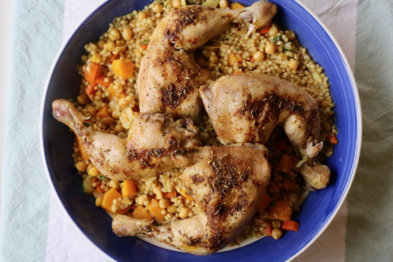 Serve Moghrabieh on a platter by spooning Lebanese couscous and topping with roast chicken legs.