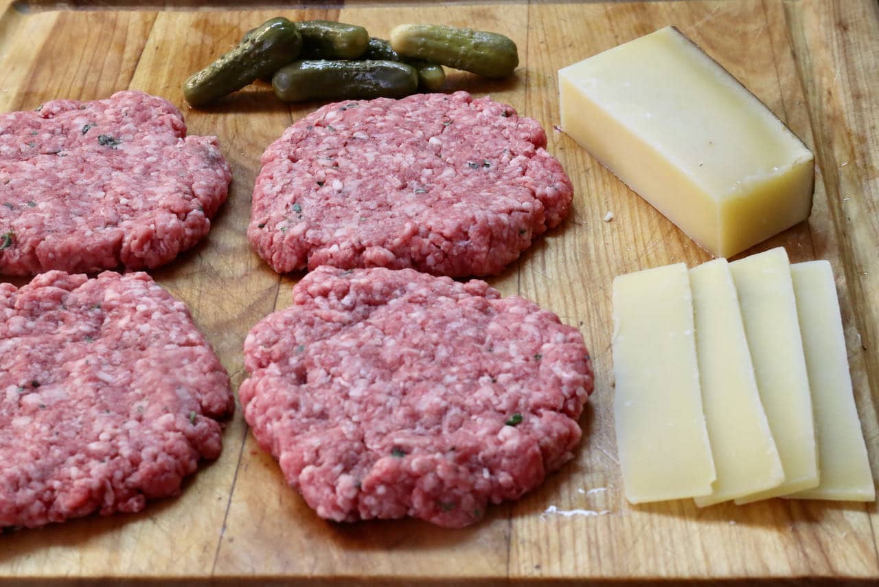 Form French Burger patties with your hands and slice comte cheese and cornichon pickles.