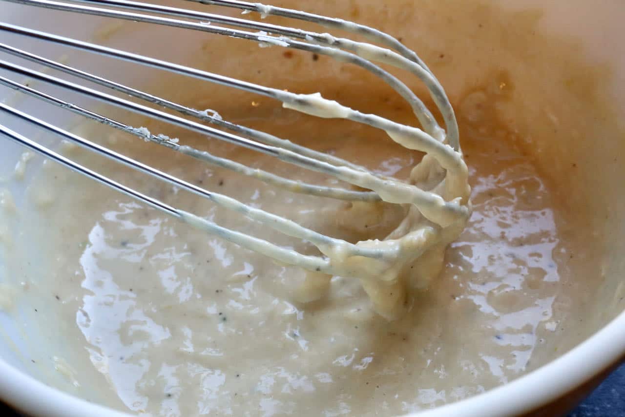 Prepare easy Tahini Caesar Dressing in a medium sized mixing bowl with a whisk until smooth and creamy.