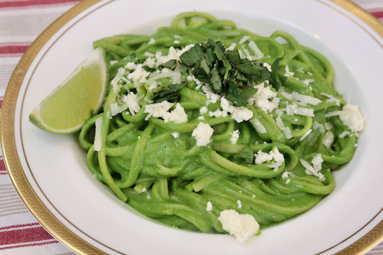 Serve Tallarines Verdes topped with queso fresco, chopped basil and a lime wedge.