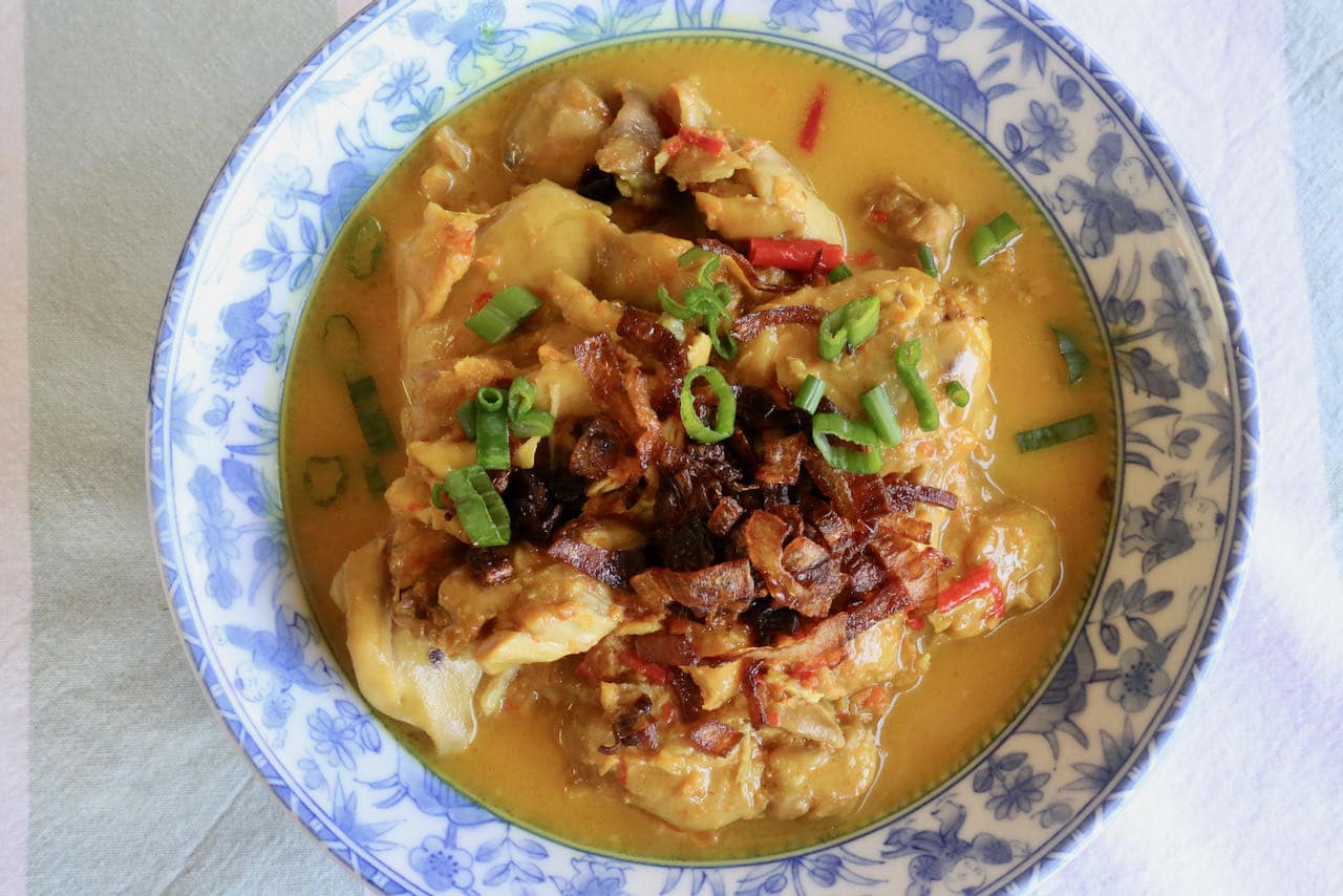 Serve Burmese Chicken Curry garnished with sliced scallions and crispy fried shallots.