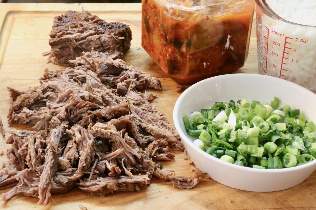 Shred beef brisket before adding it back to the Gukbap broth with kimchi and cooked rice.