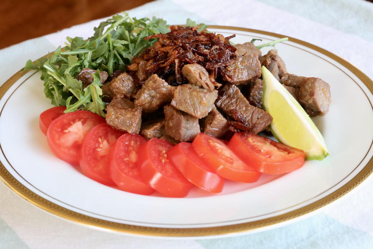 Serve Vietnamese Beef Stir Fry with sliced tomatoes, fresh greens and lime wedge.