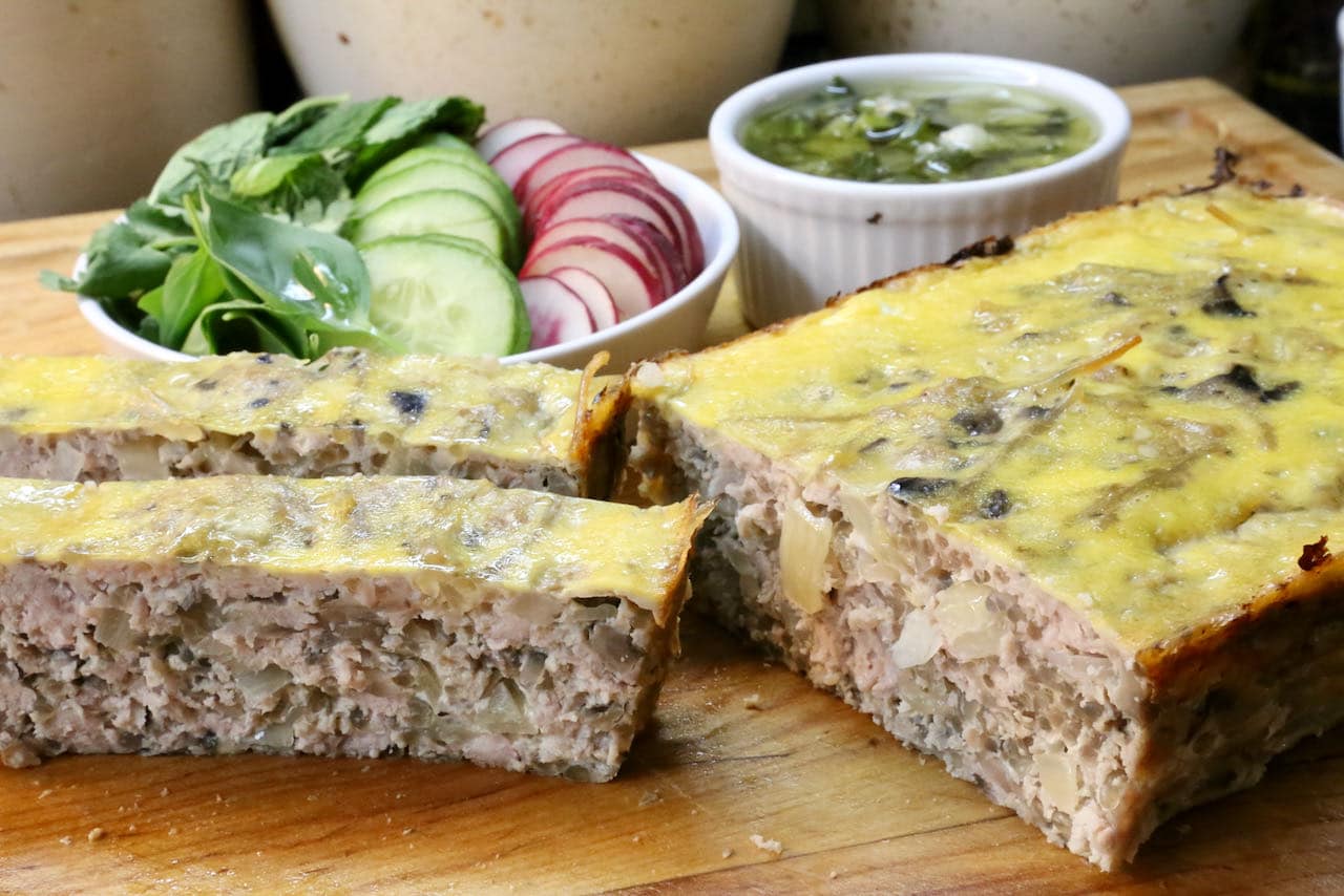 Vietnamese Meatloaf is served sliced with fresh herbs, cucumber, radish and scallion oil sauce.