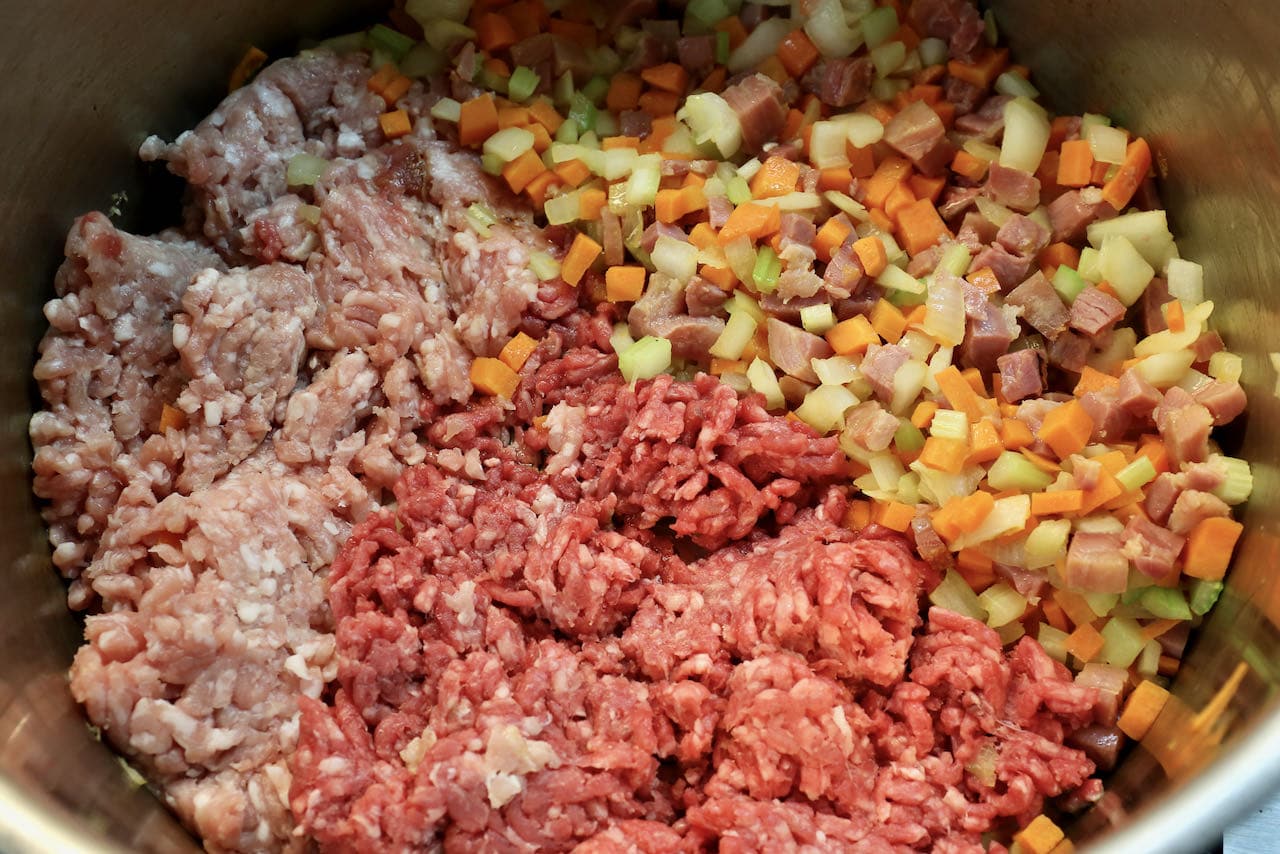 In a large pot cook the ground beef and pork with minced vegetables and pancetta. 