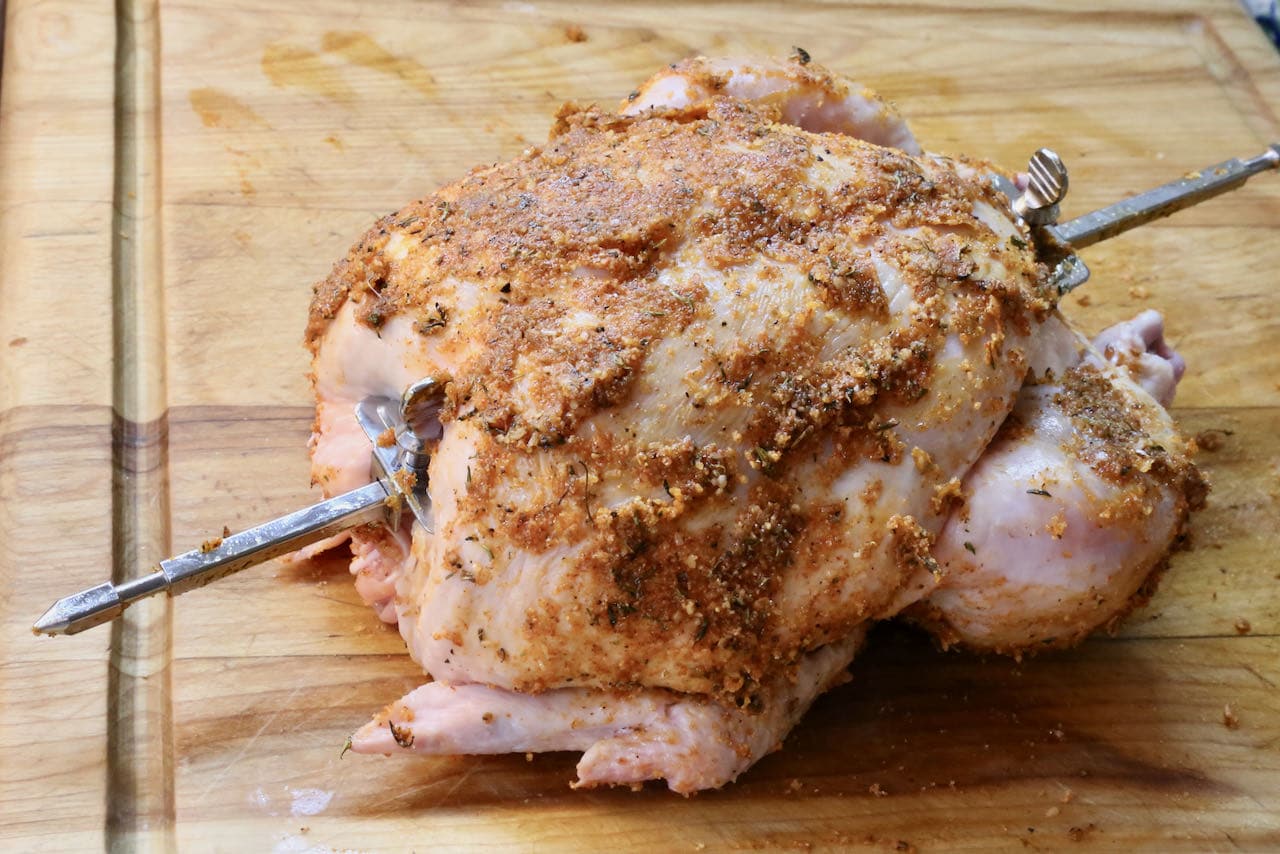 Slather a whole chicken with seasoning before skewering the bird with a rotisserie rod.