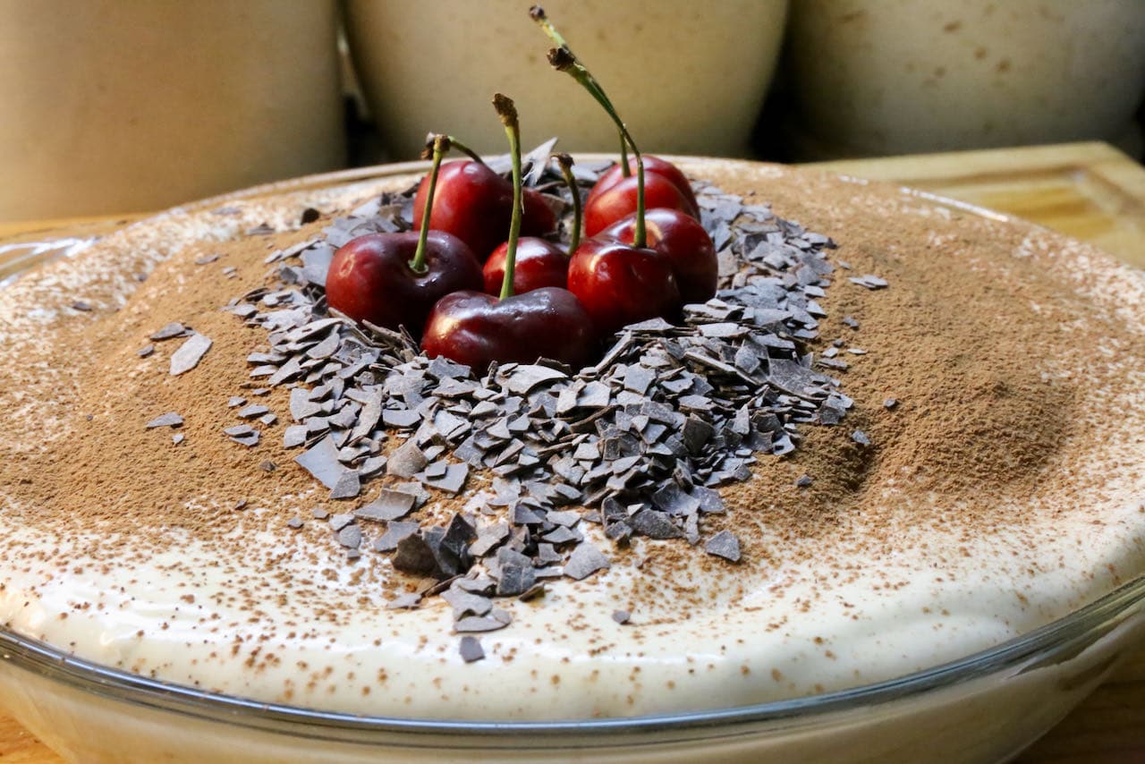 This homemade Tiramisu is garnished with fresh cherries, chopped dark chocolate and cocoa powder.