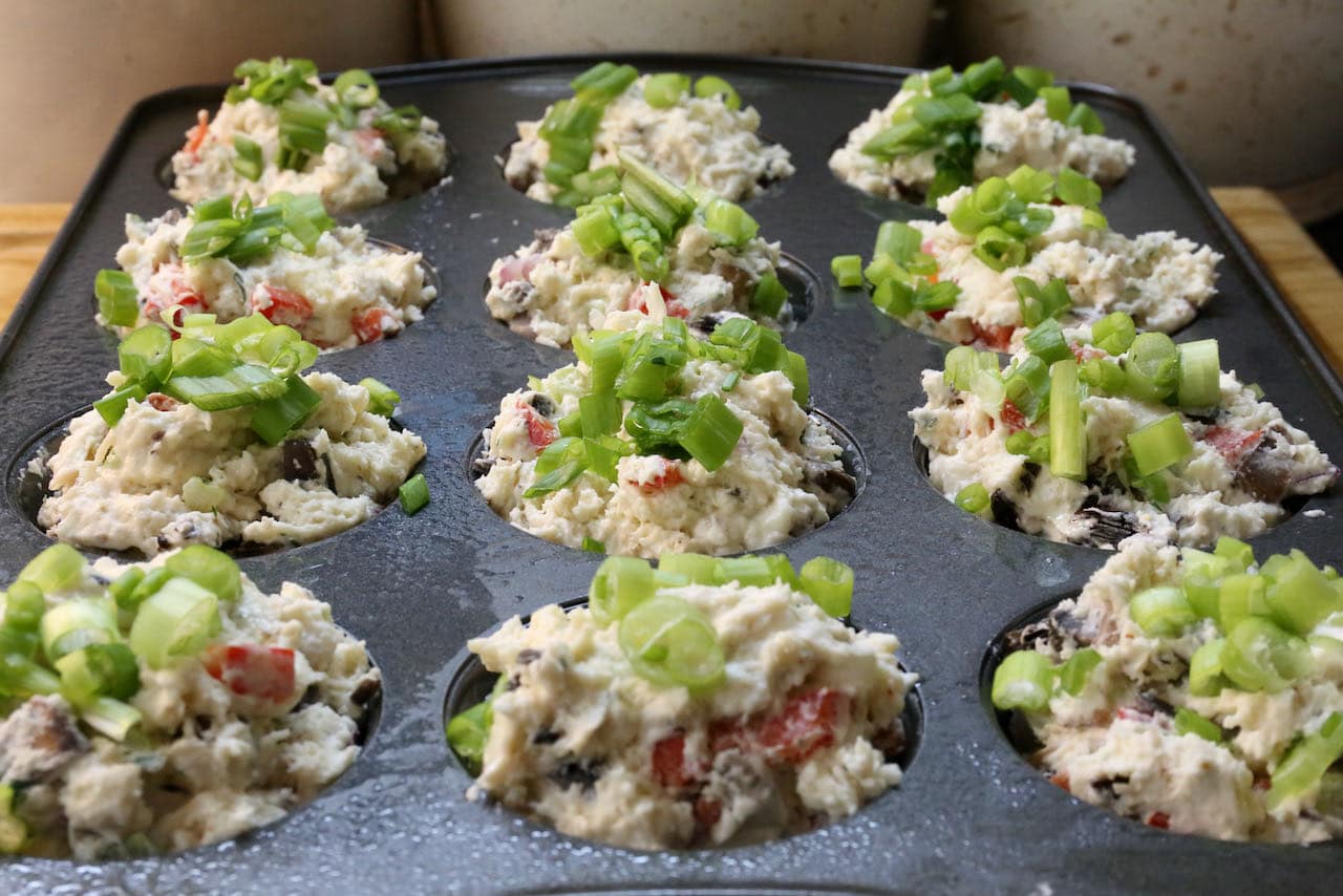 Top Savoury Vegetable Muffins with chopped scallions before baking in the oven.
