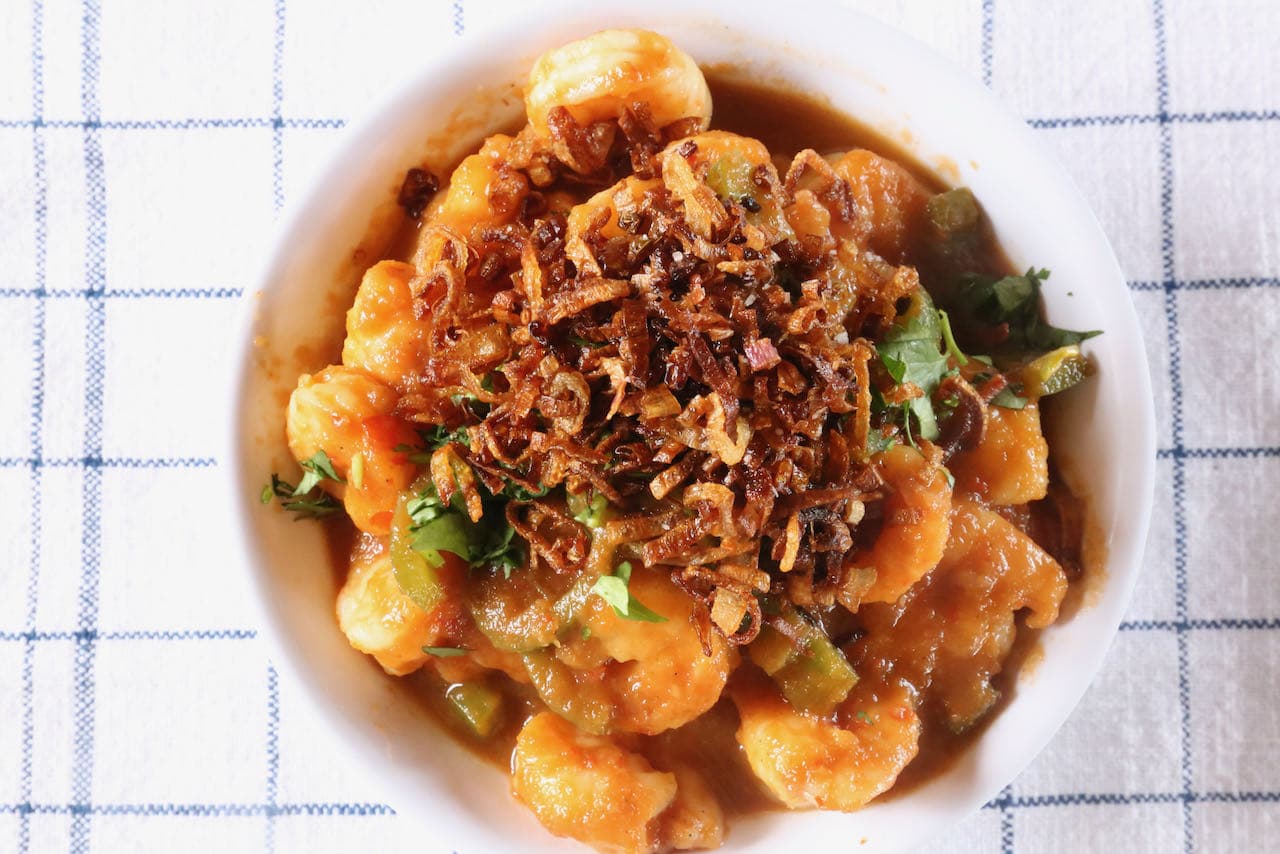 Garnish Tamarind Prawn Curry with fried shallots and cilantro.