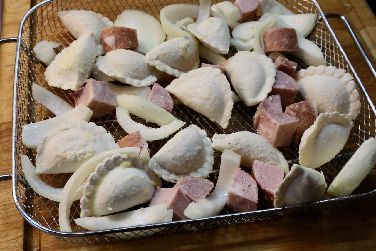 Spread out onions, sausage and pierogies on a basket before cooking in the air fryer. 