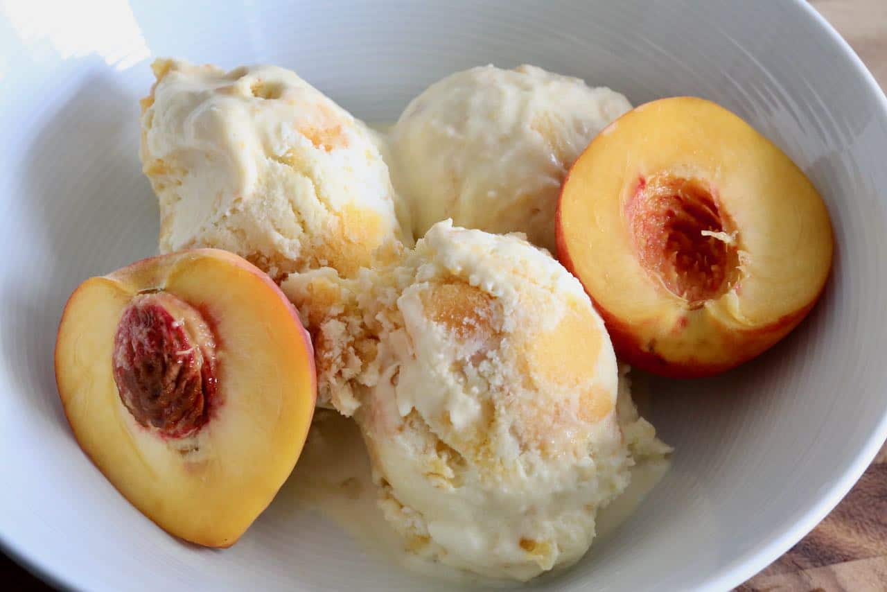 Serve scoops of homemade ice cream with slices of fresh peach.