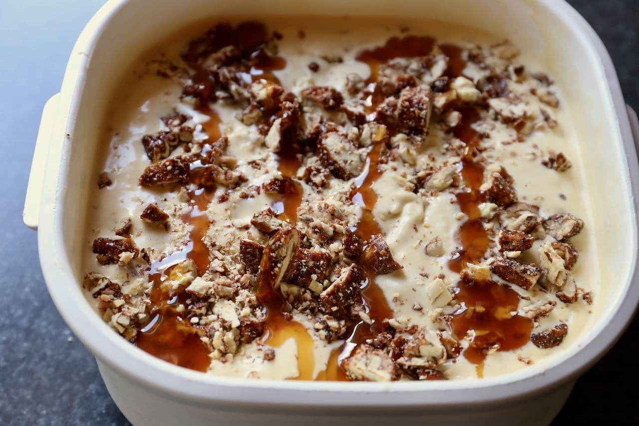 Top ice cream base with chopped candied praline pecans and caramel sauce before freezing.