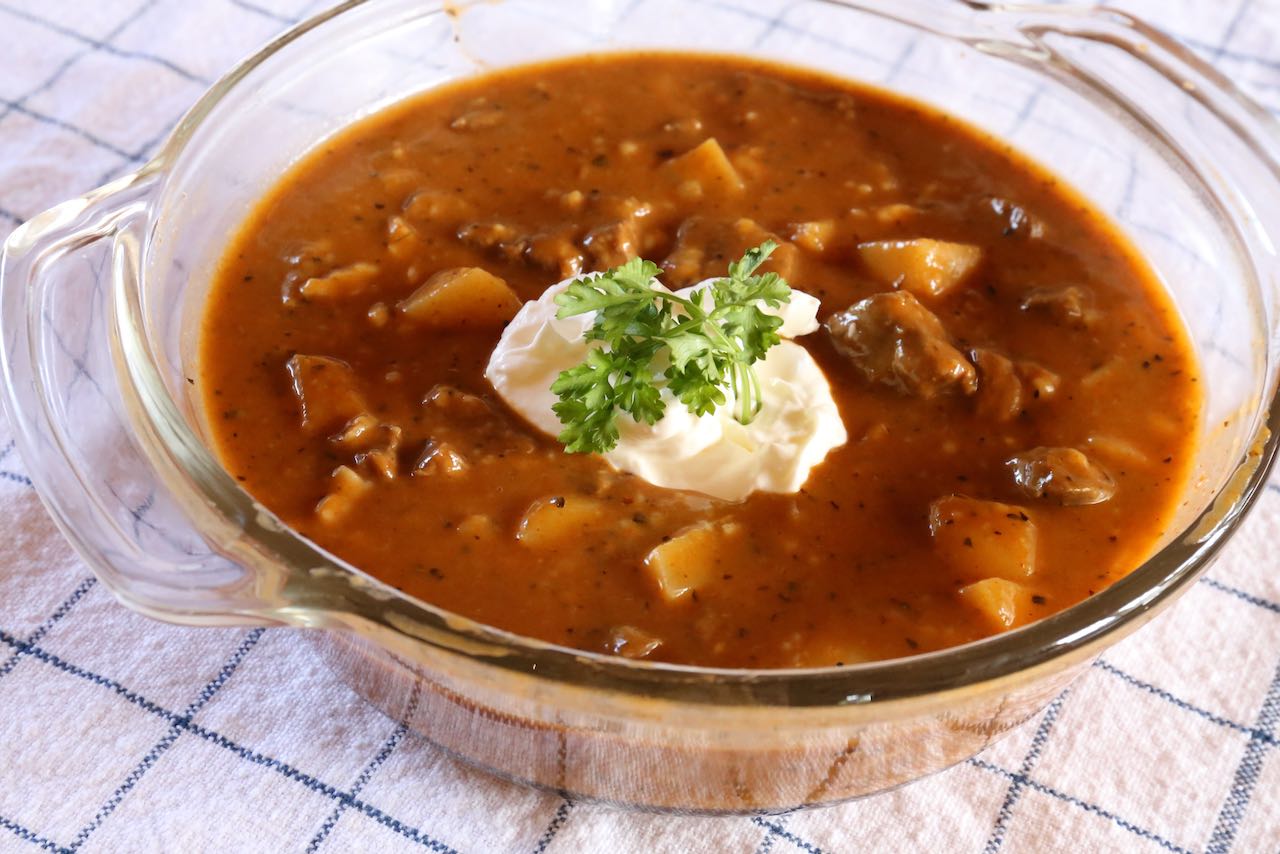 Serve Czech Beef Goulash topped with sour cream and parsley.