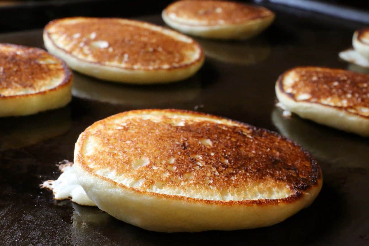 Gently flip Oladushki pancakes to ensure they are browned on both sides.