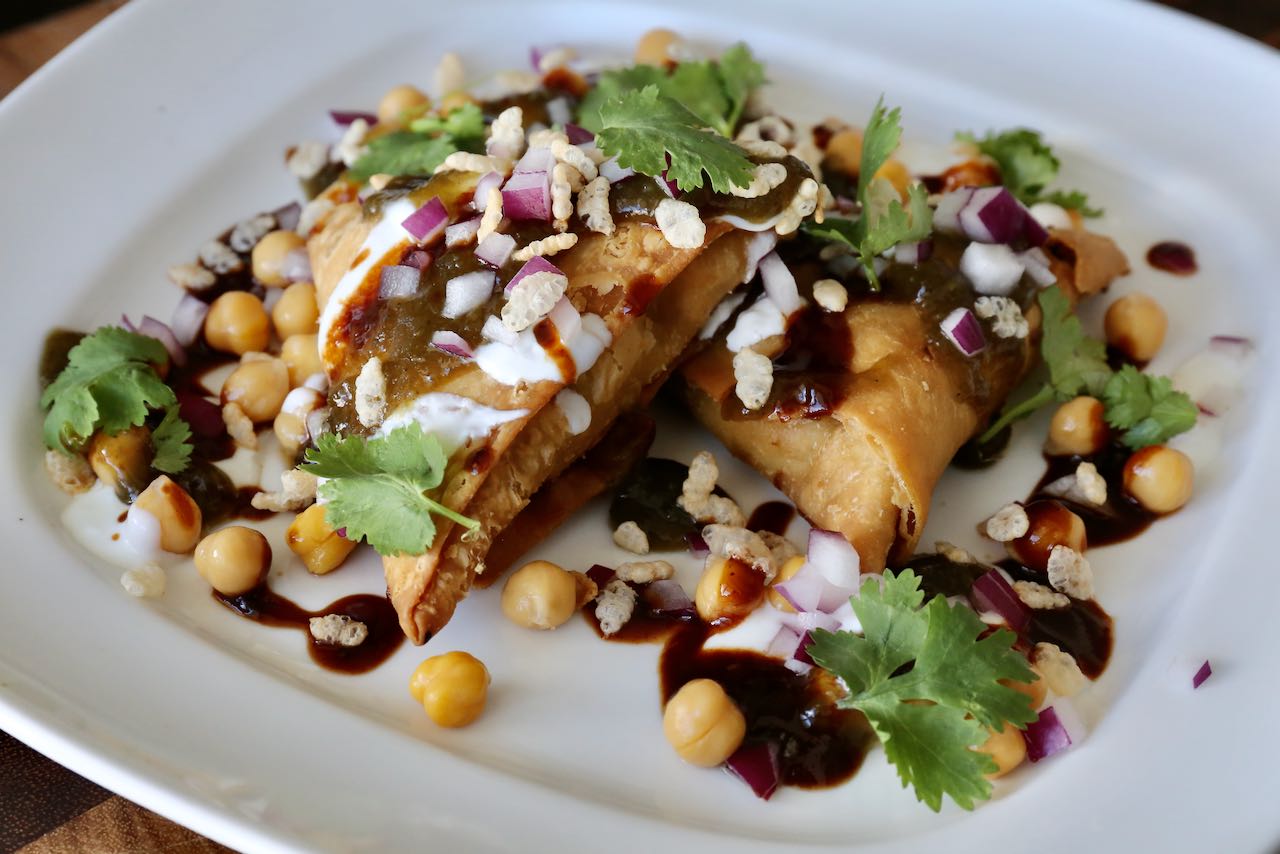 Garnish Samosa Chaat with cilantro leaves, puffed rice and minced red onions.