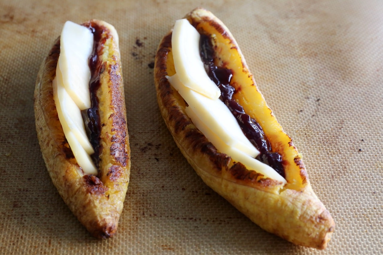 Maduro con Queso is a Latin dish featuring baked plantain stuffed with cheese and guava jam.