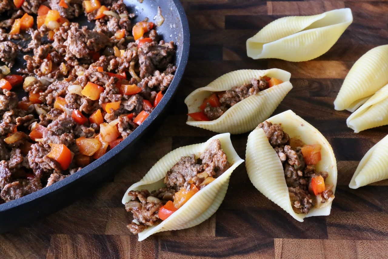 Fill cooked pasta shells with ground beef filling. 