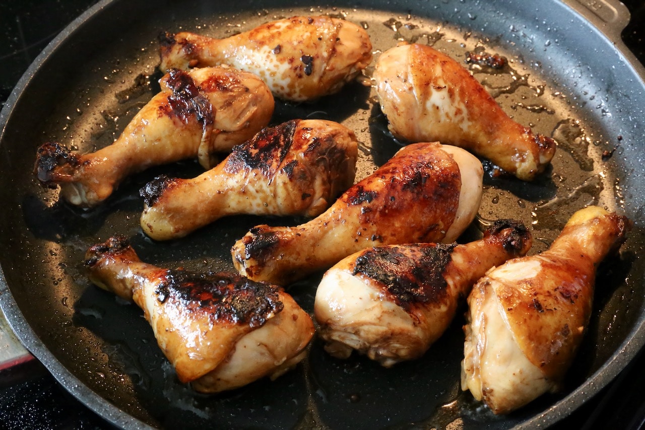Cook the marinated chicken drumsticks in a nonstick skillet until browned and crispy.