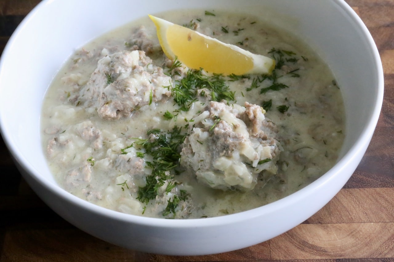 Serve authentic Giouvarlakia with a lemon wedge and garnished with fresh dill.
