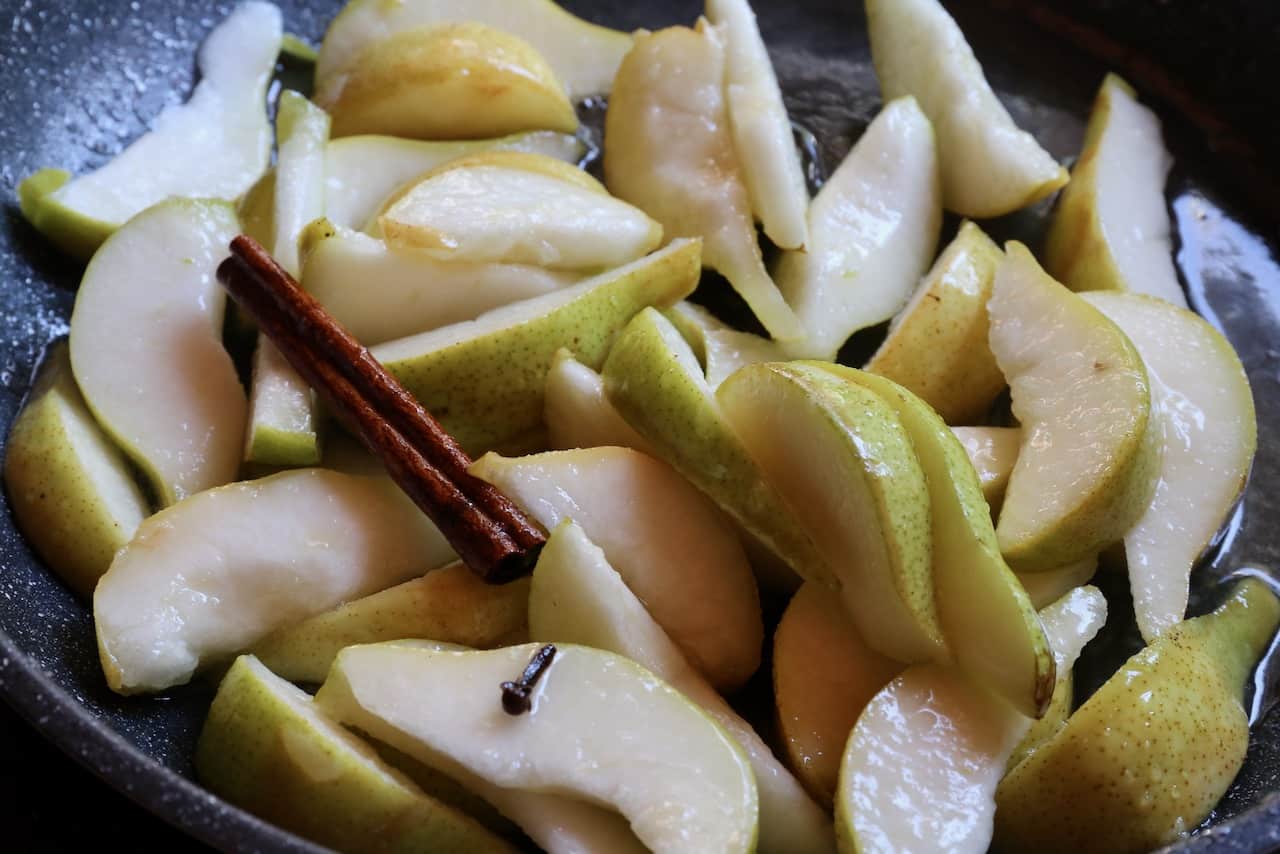 Stewed pears are cooked in a skillet with spices like cinnamon.